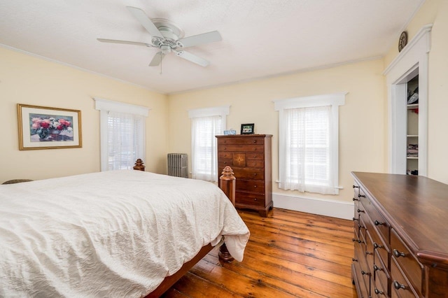bedroom featuring a ceiling fan, wood-type flooring, ornamental molding, and baseboards
