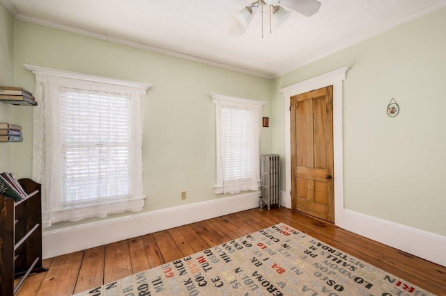 unfurnished bedroom with multiple windows, radiator, and hardwood / wood-style floors