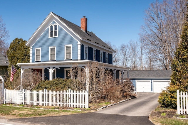 country-style home with a porch, a chimney, a fenced front yard, and a detached garage