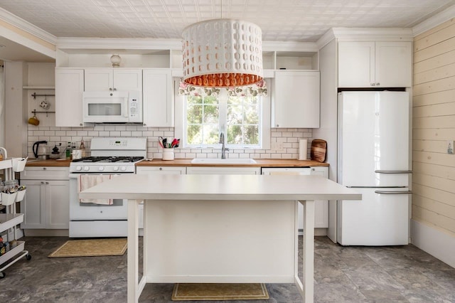 kitchen featuring butcher block countertops, ornamental molding, white appliances, decorative backsplash, and a sink