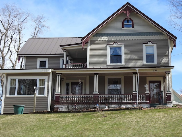 view of front of property with a standing seam roof, a balcony, a front lawn, and covered porch