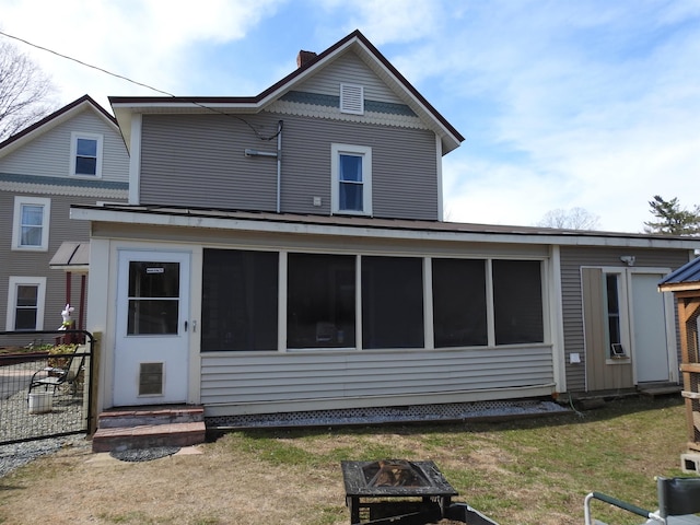 rear view of house featuring an outdoor fire pit, a sunroom, and a chimney