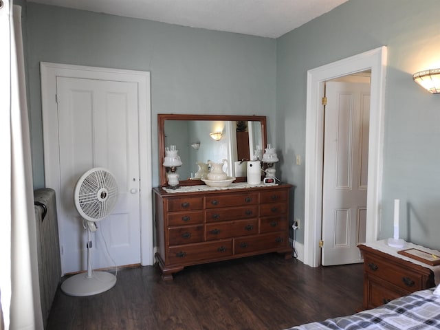 bedroom featuring dark wood-type flooring, radiator heating unit, and baseboards