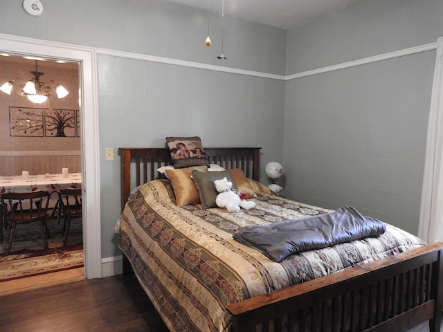 bedroom with wood finished floors, an inviting chandelier, and ensuite bathroom