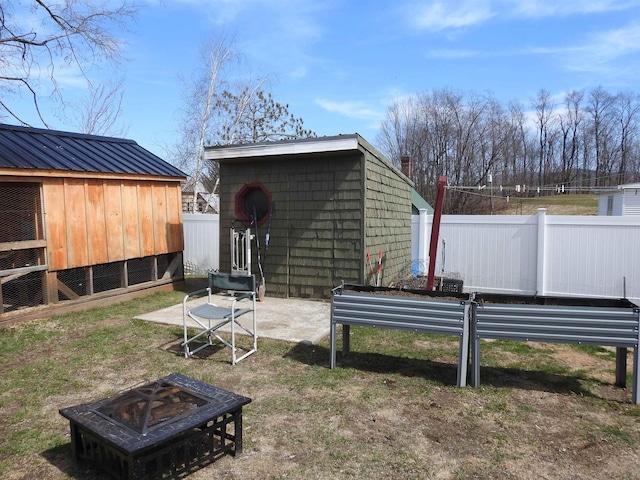 view of yard featuring an outdoor fire pit, fence, and an outdoor structure