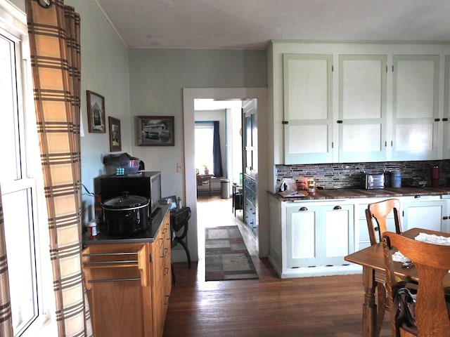 kitchen with dark wood-type flooring, white cabinetry, backsplash, and dark countertops