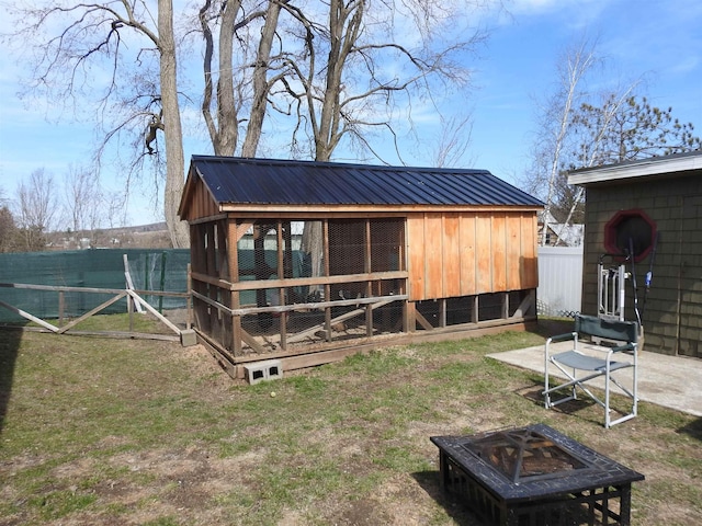 rear view of house with an outdoor structure, a fire pit, exterior structure, metal roof, and fence