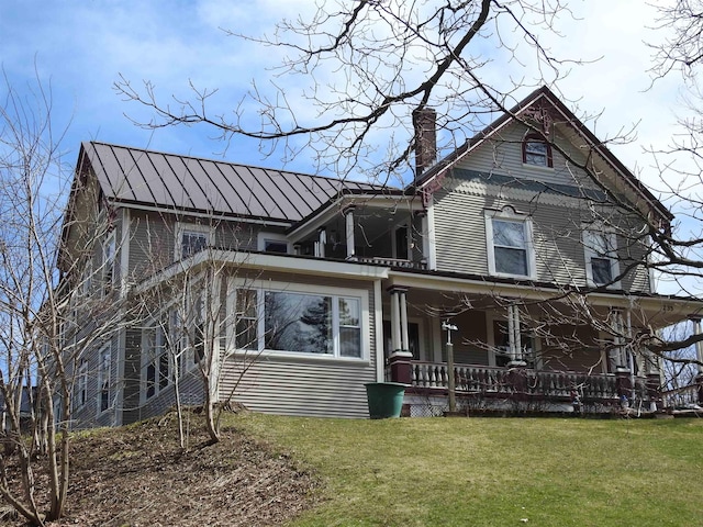 view of front of property with a porch, a chimney, and a front lawn
