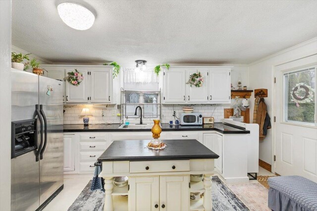 117A Chases Grove Rd, Derry, NH 03038 - kitchen with white microwave, a textured ceiling, a sink, stainless steel fridge, and dark countertops