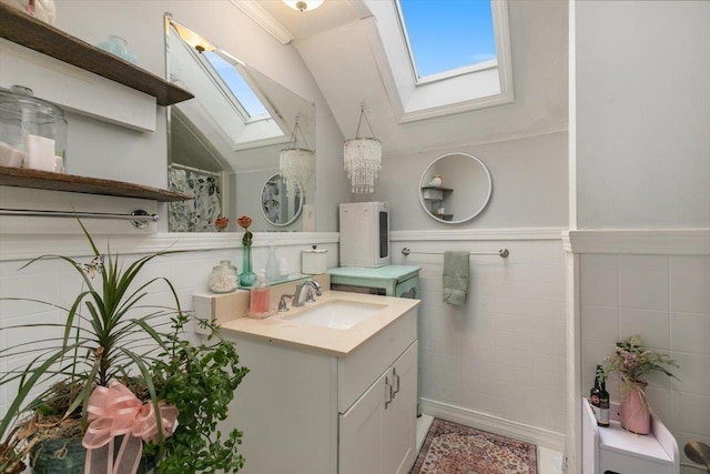 117A Chases Grove Rd, Derry, NH 03038 - full bath featuring vaulted ceiling with skylight, vanity, wainscoting, and tile walls