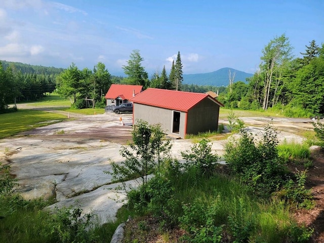 195 Curtis Rd, Morgan, VT 05853 - view of home's exterior with a metal roof, a mountain view, an outbuilding, and a view of trees