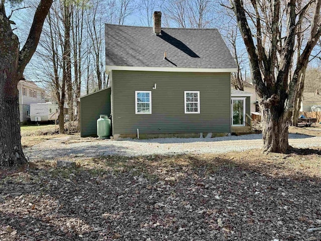 view of side of property with a chimney and roof with shingles