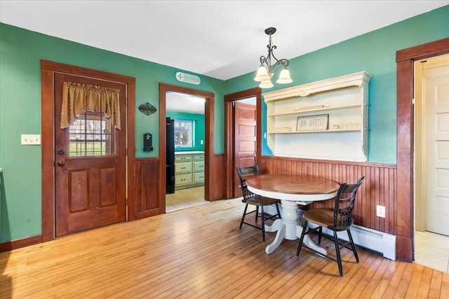 dining room featuring wood walls, a wainscoted wall, and light wood-style floors