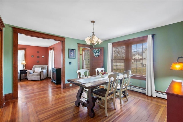 dining room with a baseboard radiator, hardwood / wood-style floors, an inviting chandelier, and baseboards