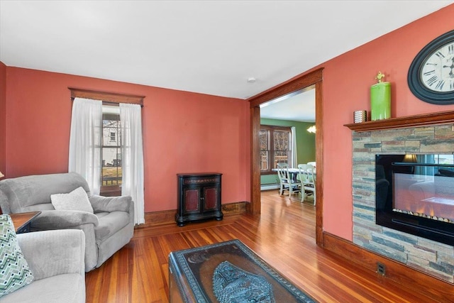 living area with a stone fireplace, baseboards, and wood finished floors
