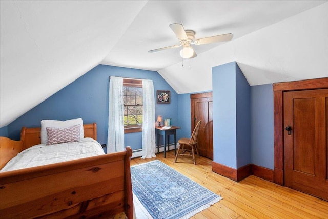 bedroom with baseboards, vaulted ceiling, a ceiling fan, light wood-style floors, and a baseboard radiator