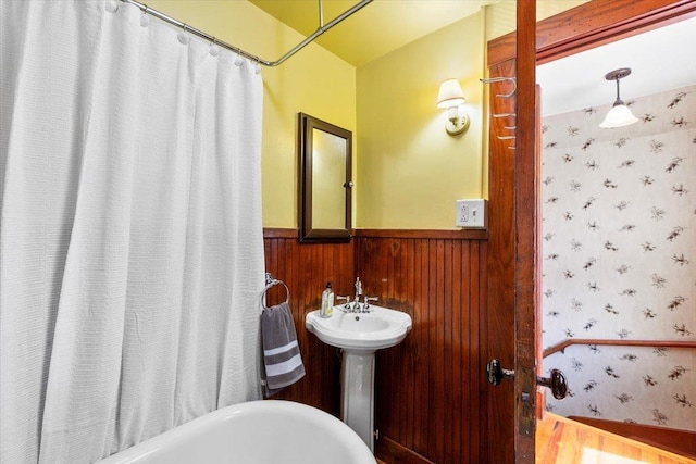 full bathroom with wainscoting, a sink, and wallpapered walls