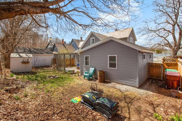 rear view of property with a storage shed, fence, and an outbuilding