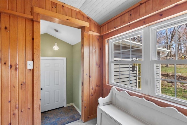 foyer entrance featuring wooden walls and vaulted ceiling