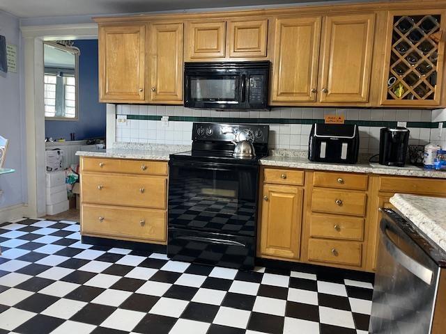 kitchen featuring dark floors, light countertops, backsplash, and black appliances