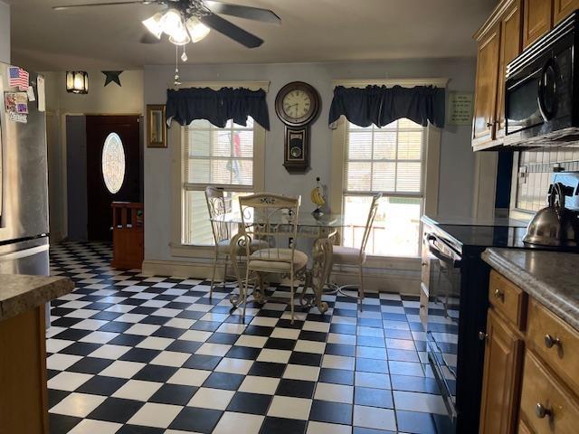 kitchen featuring brown cabinetry, black appliances, a ceiling fan, and a healthy amount of sunlight