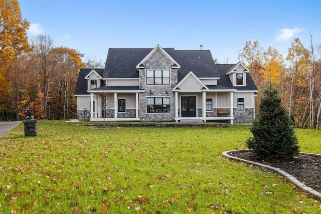 back of house featuring board and batten siding, a yard, covered porch, and stone siding