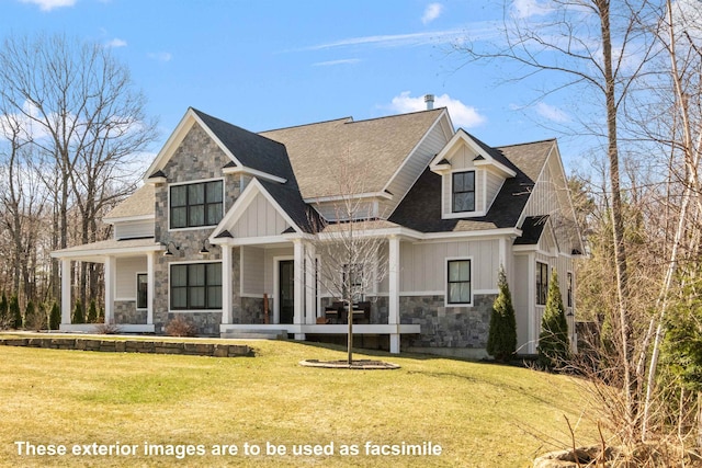 view of front of property featuring roof with shingles, a front yard, and stone siding