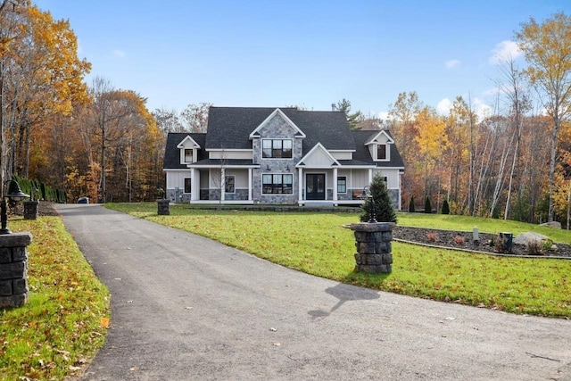 view of front of house with a front yard, stone siding, and covered porch