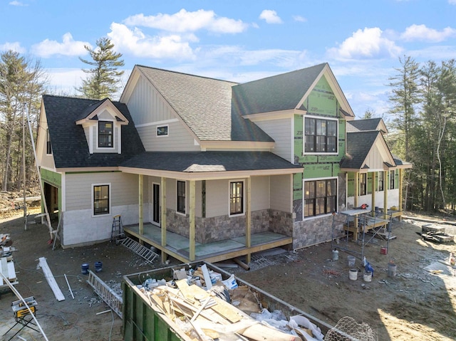 view of front of property with a sunroom, roof with shingles, and stone siding