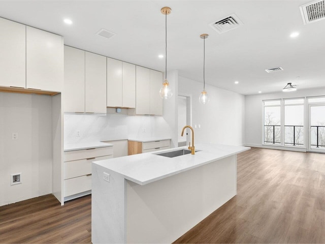 125 Cambrian Way Unit 605, Burlington, VT 05401 - kitchen featuring a sink, white cabinetry, wood finished floors, an island with sink, and hanging light fixtures