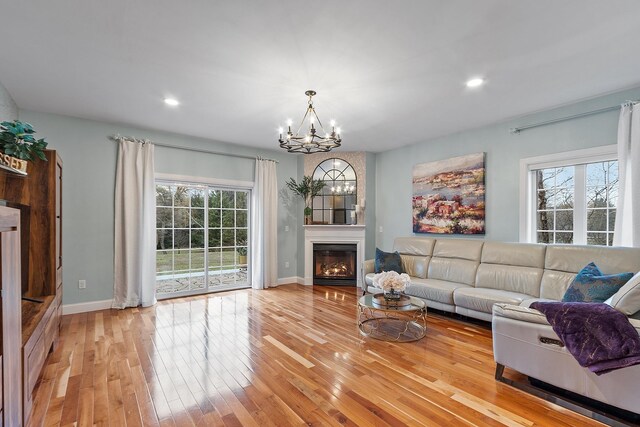 living area with a glass covered fireplace, baseboards, a chandelier, recessed lighting, and hardwood / wood-style flooring