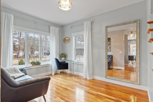 sitting room with wood-type flooring, visible vents, and baseboards