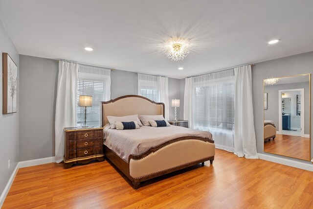 bedroom with light wood finished floors, a notable chandelier, and baseboards