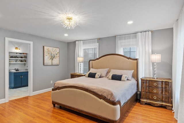 bedroom featuring light wood-style flooring, an inviting chandelier, ensuite bath, and recessed lighting