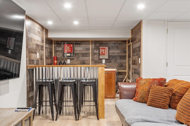 bar with a bar, recessed lighting, and wood walls