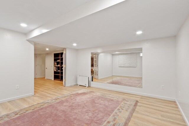 finished below grade area featuring wood finished floors, radiator heating unit, baseboards, and recessed lighting