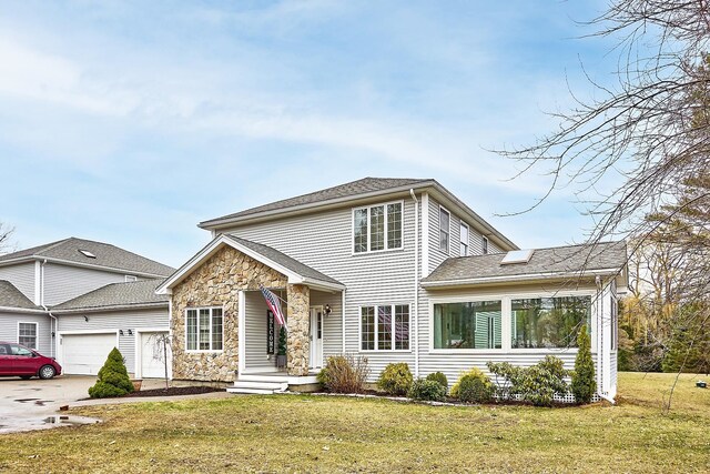 traditional-style house with driveway, an attached garage, stone siding, and a front lawn