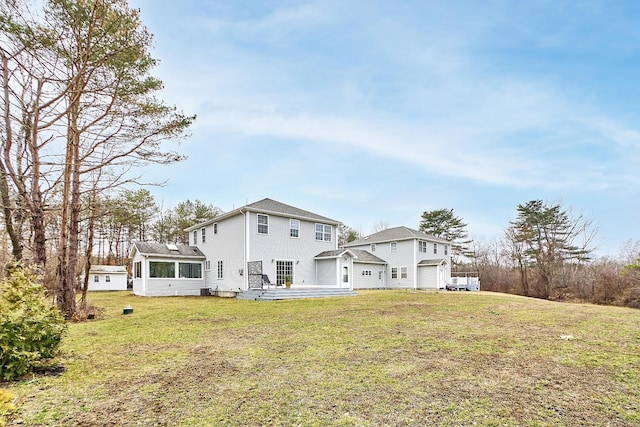 rear view of house with an attached garage, a lawn, and a sunroom