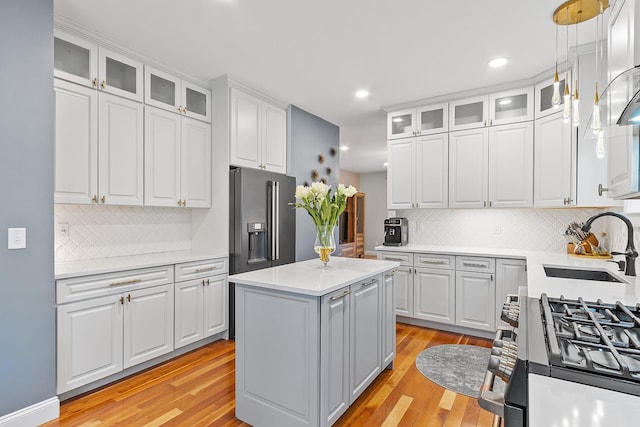 kitchen featuring range with gas cooktop, high end fridge, light wood-style flooring, and a sink