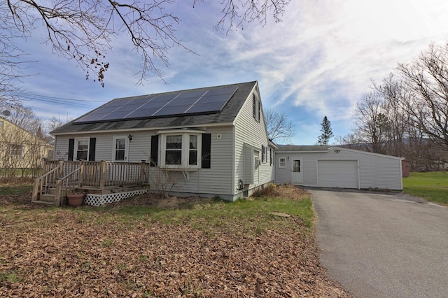 view of front of house with roof with shingles, driveway, solar panels, and a wooden deck