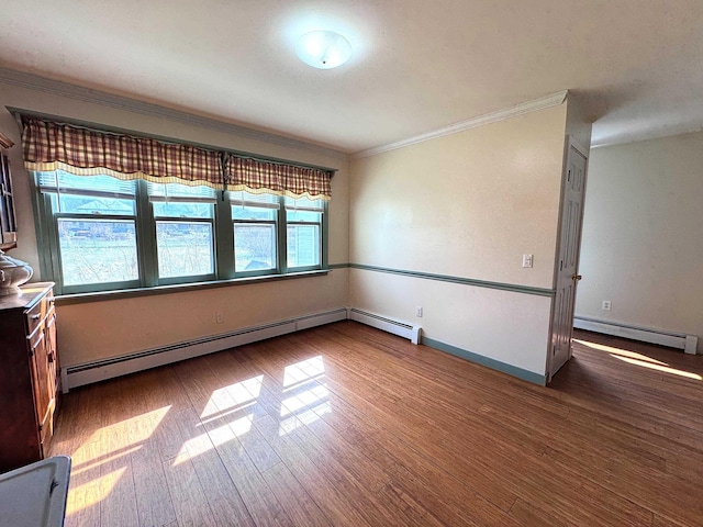 spare room with crown molding, baseboards, a baseboard heating unit, and wood finished floors