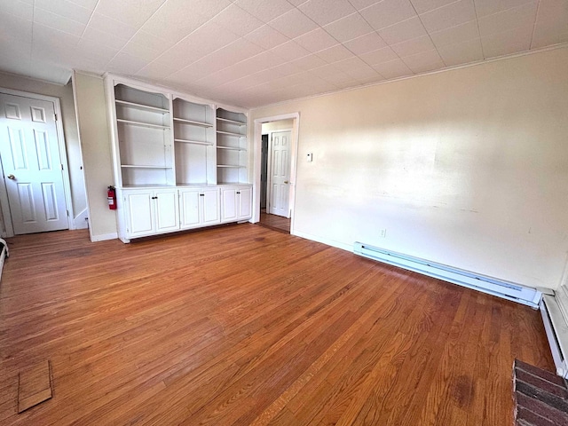 unfurnished living room featuring built in shelves, a baseboard radiator, baseboards, and wood finished floors