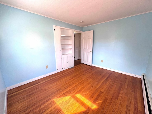 unfurnished bedroom featuring ornamental molding, baseboards, wood finished floors, and baseboard heating