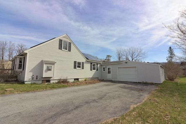 exterior space featuring an outbuilding, driveway, a detached garage, and solar panels