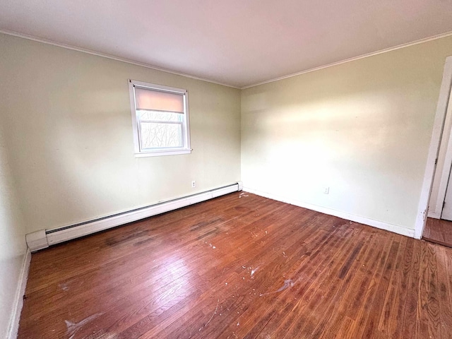 empty room with crown molding, wood finished floors, a baseboard heating unit, and baseboards