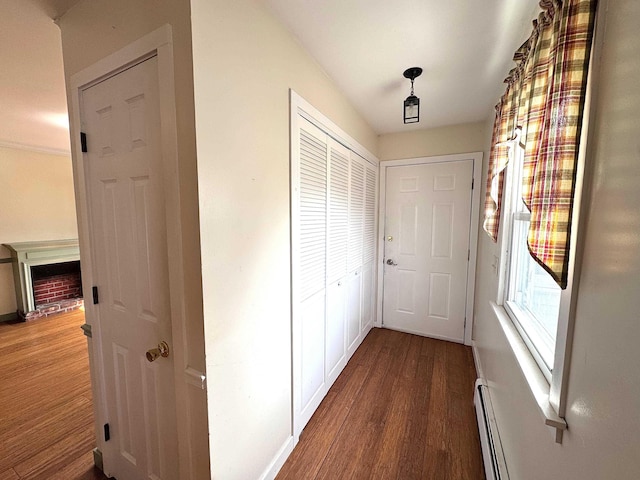 corridor with a baseboard radiator, wood finished floors, and baseboards