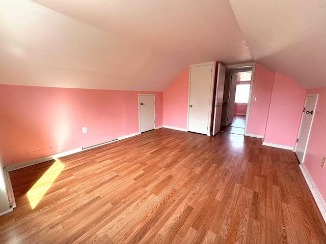 additional living space featuring lofted ceiling, baseboards, and wood finished floors