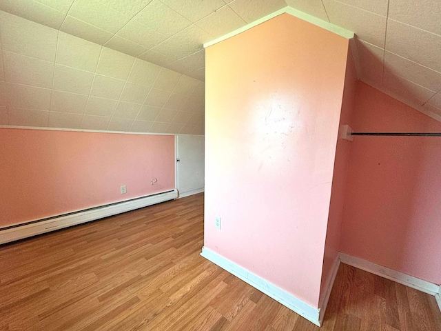 additional living space featuring baseboards, wood finished floors, vaulted ceiling, and baseboard heating