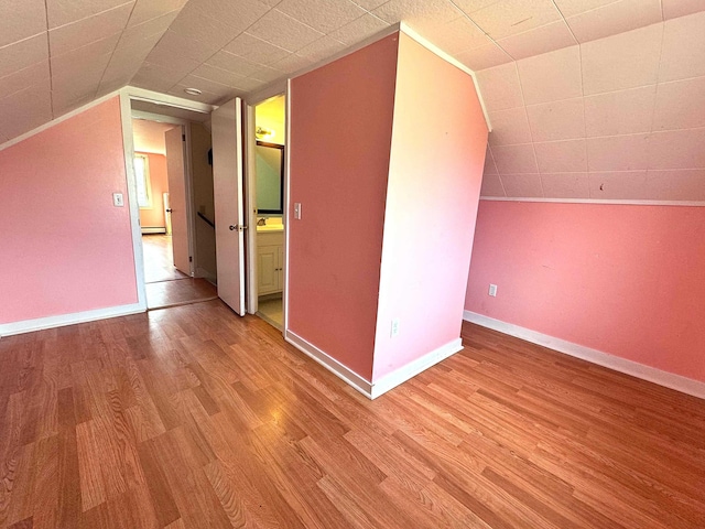 bonus room featuring baseboards, lofted ceiling, wood finished floors, and baseboard heating