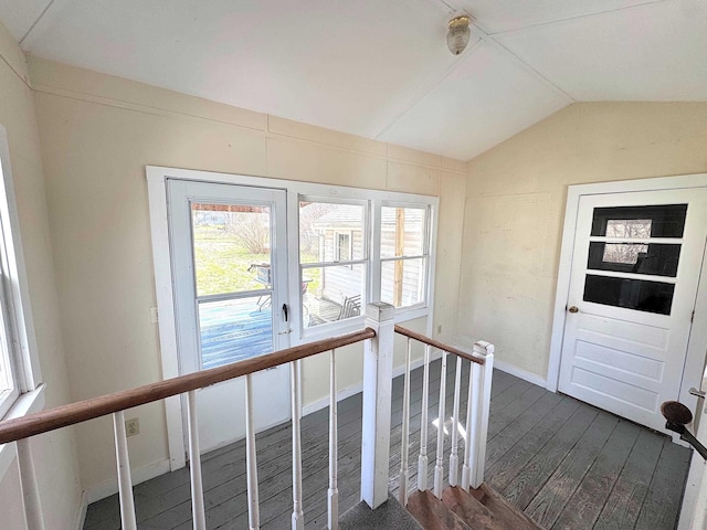 stairway with wood finished floors, baseboards, vaulted ceiling, and a wealth of natural light